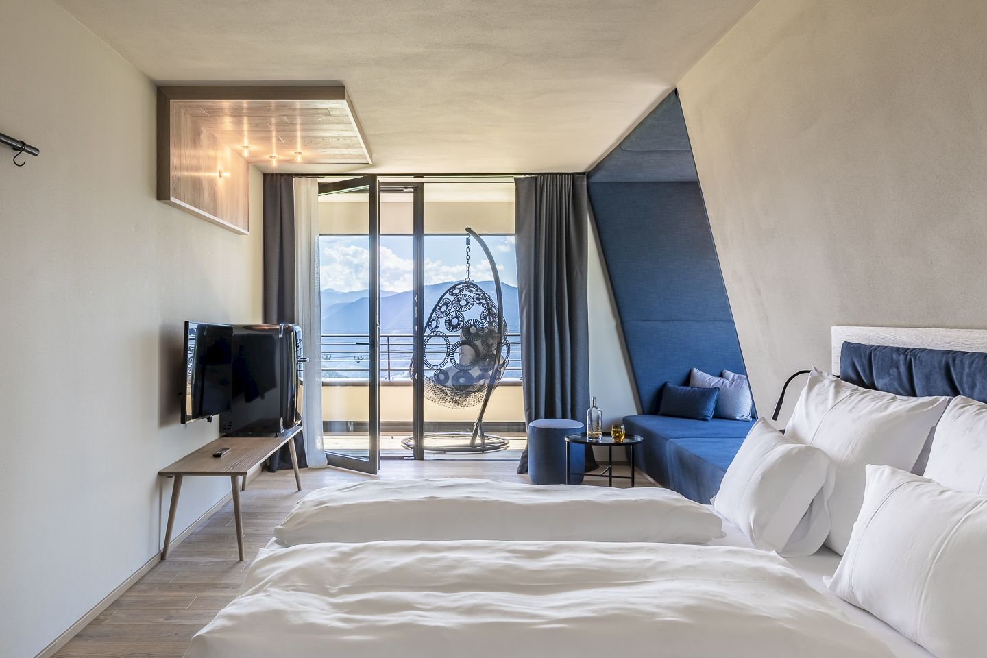 Lorenzi Suite con due letti, balcone con poltrona sospesa e vista sulle montagne.