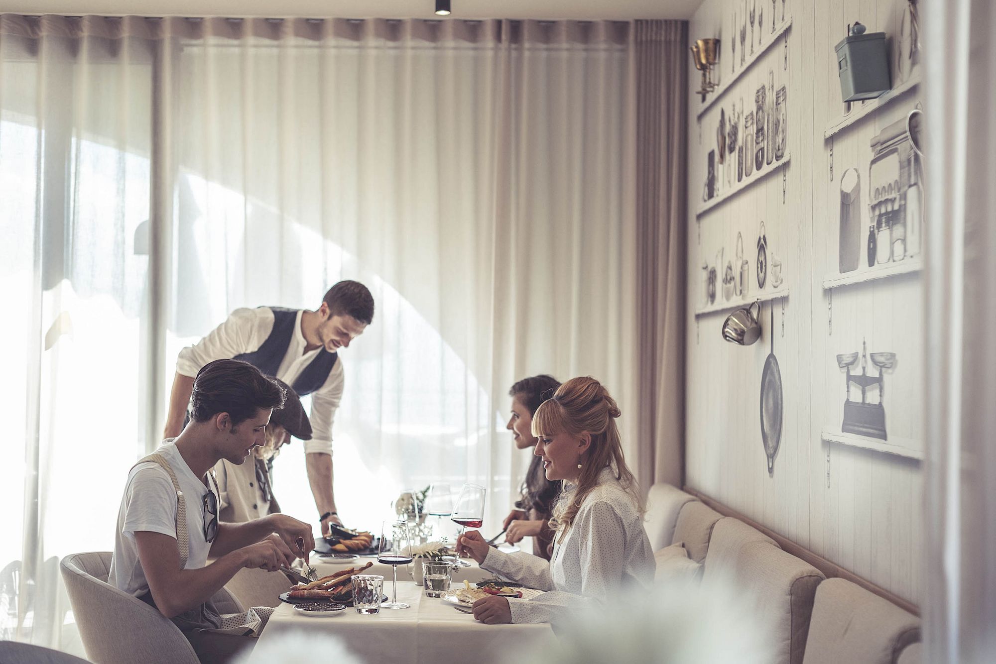 Eine Gruppe von vier Leuten speist im eleganten Puro Restaurant, während ein Kellner sie bedient.