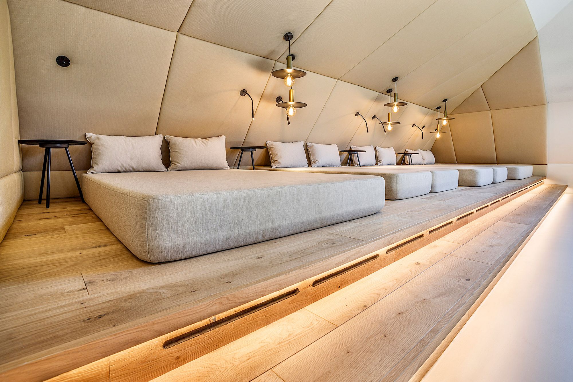 Gloriette Guesthouse chill area con grandi divani, pavimento in legno e lampade moderne appese al soffitto inclinato.