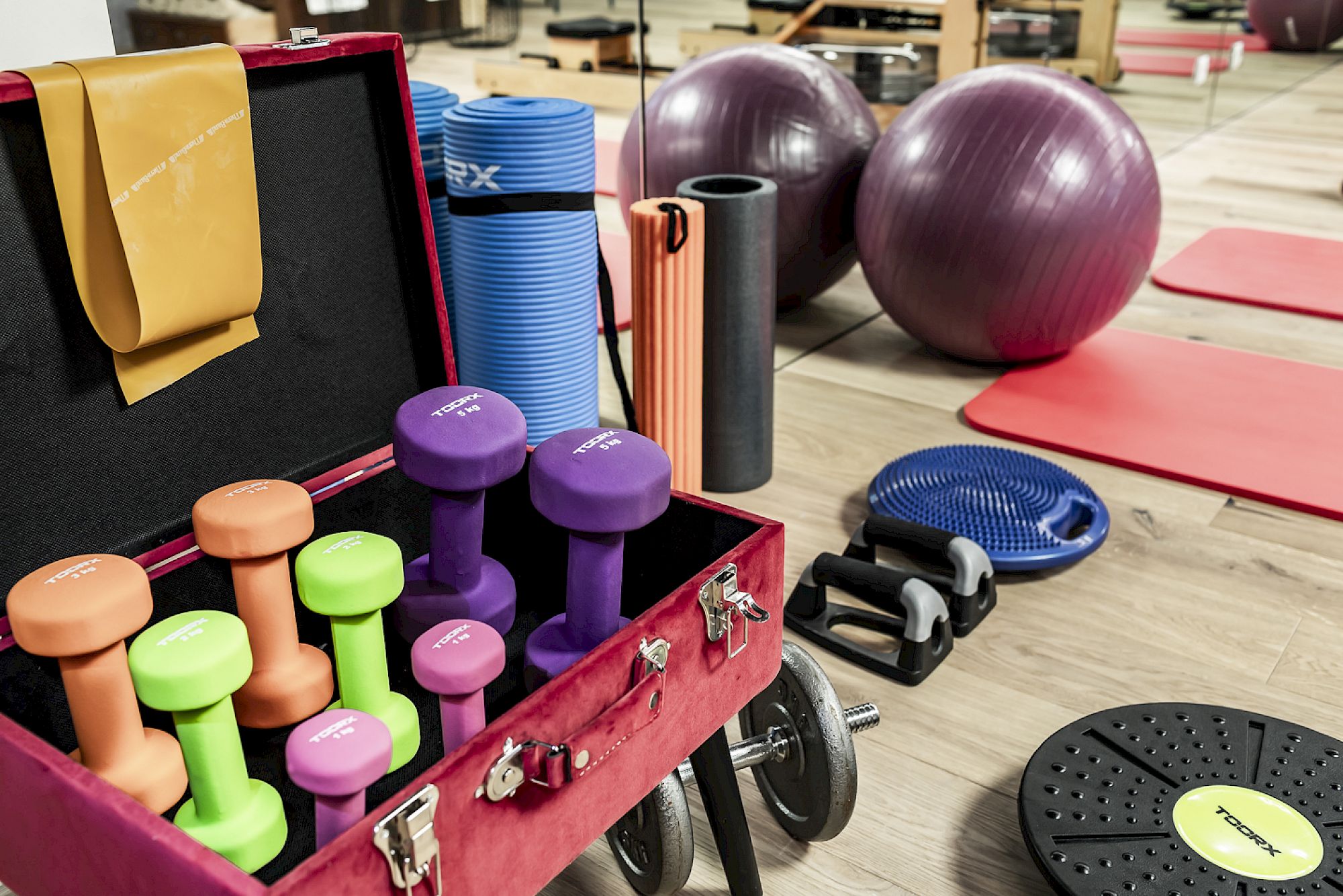 Diverse fitness equipment at Gloriette Guesthouse like dumbbells, exercise balls, and mats in a bright training room.