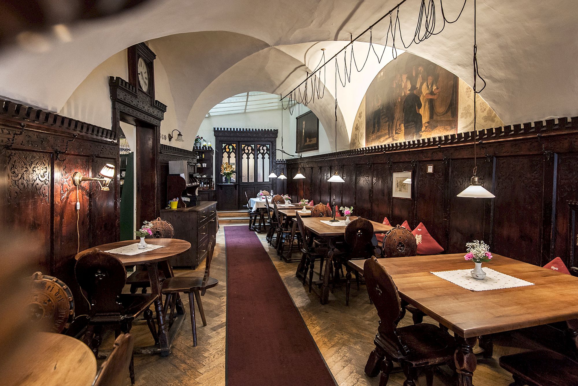 Interno accogliente di un ristorante tradizionale con boiserie in legno e lunghi tavoli.