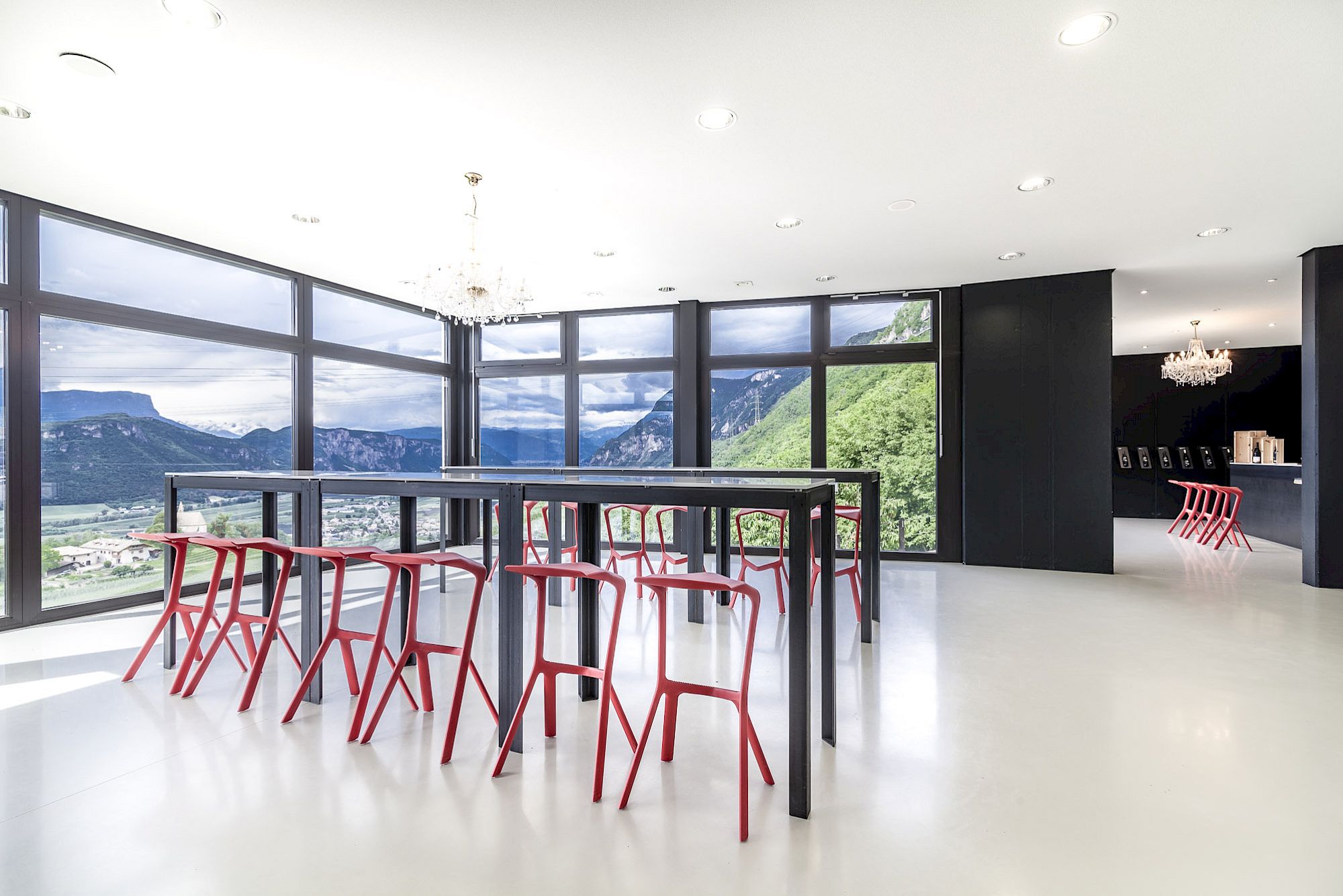 Sala luminosa con ampie finestre, sgabelli eleganti e vista mozzafiato sulle montagne.