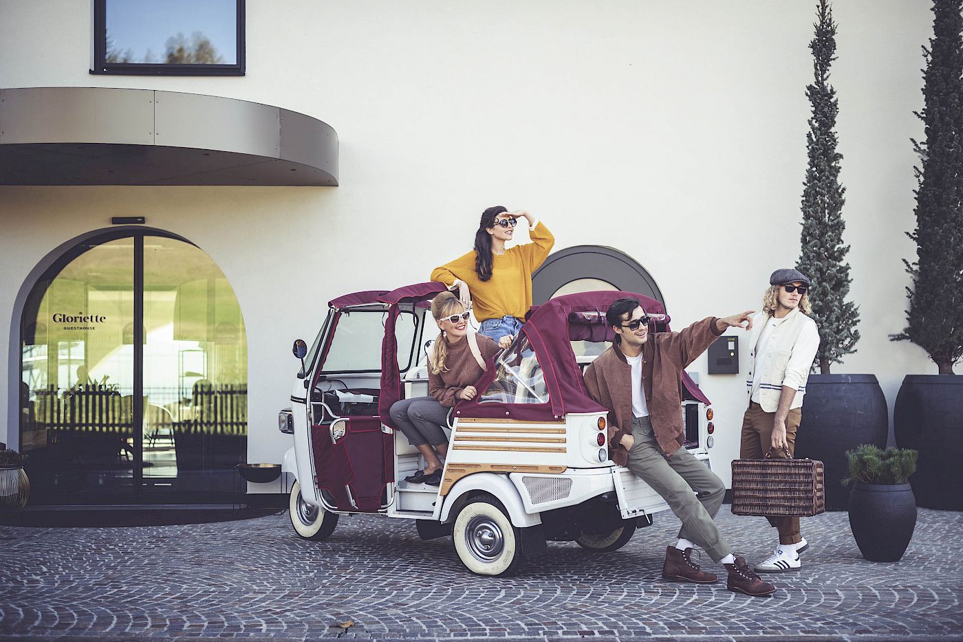 Quattro persone posano con un veicolo retrò a tre ruote davanti al Gloriette Guesthouse.