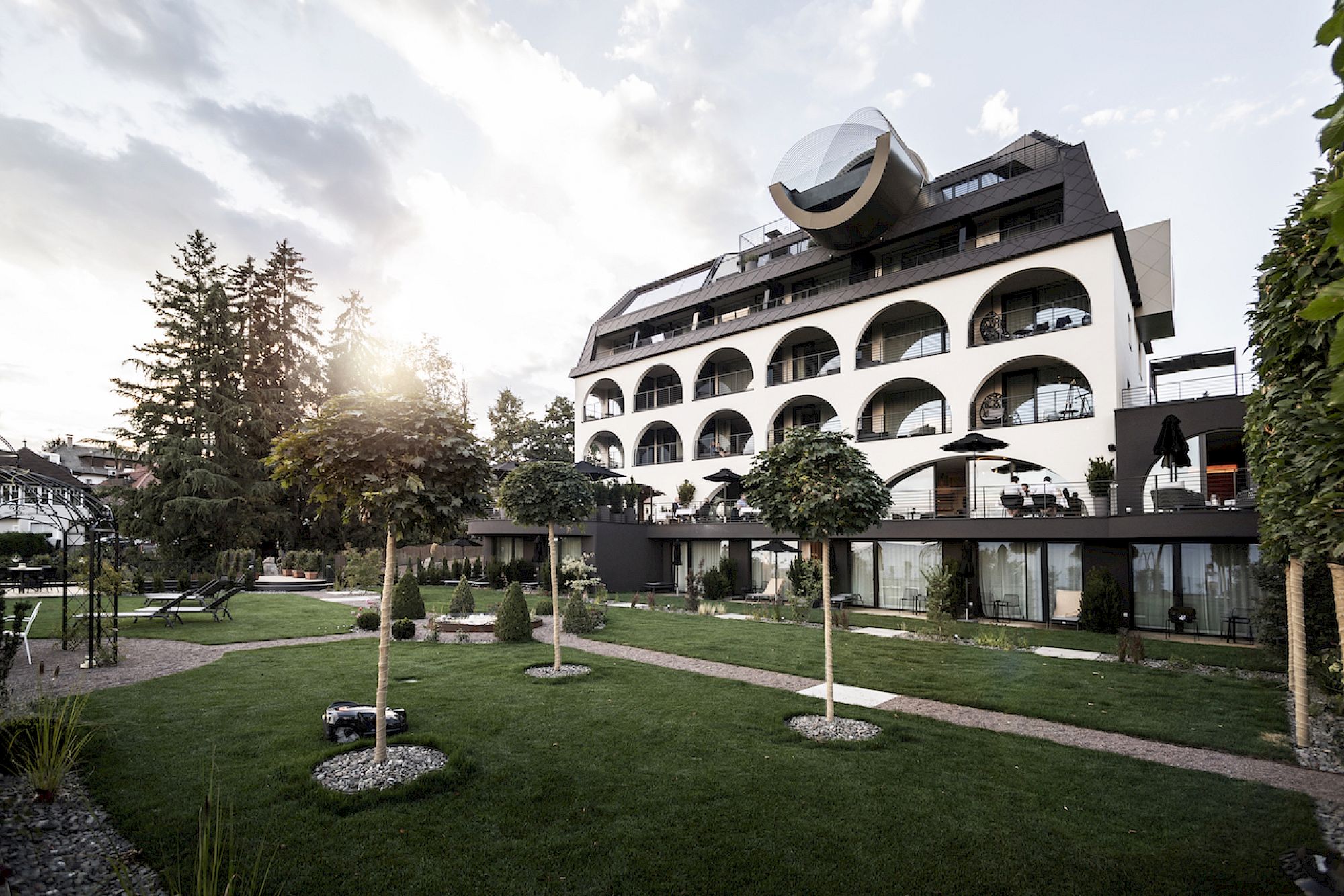 Gloriette Guesthouse dall´esterno con balconi arcuati, circondato da un giardino curato e alberi al tramonto.