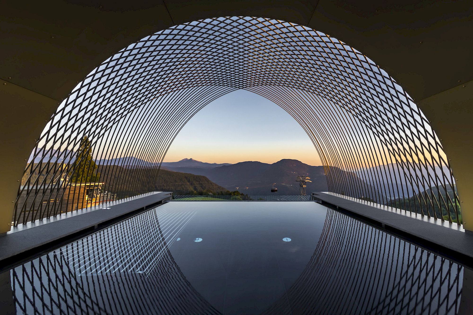 Infinity pool con vista su un paesaggio montuoso al tramonto. Design futuristico.