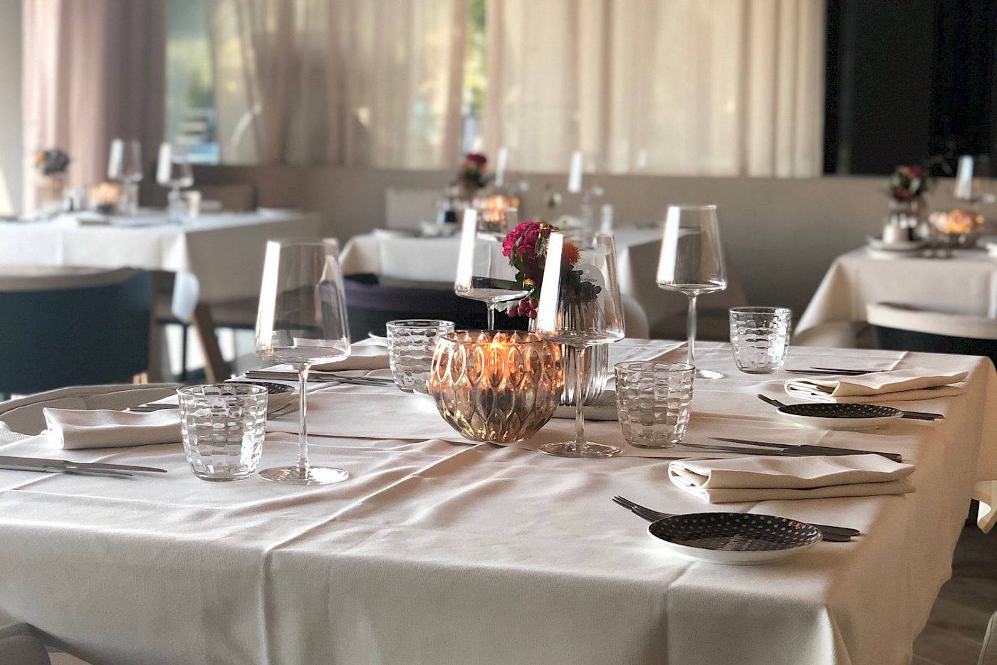 Ristorante elegante con tavoli apparecchiati, luci soffuse e arredi moderni. Atmosfera accogliente.