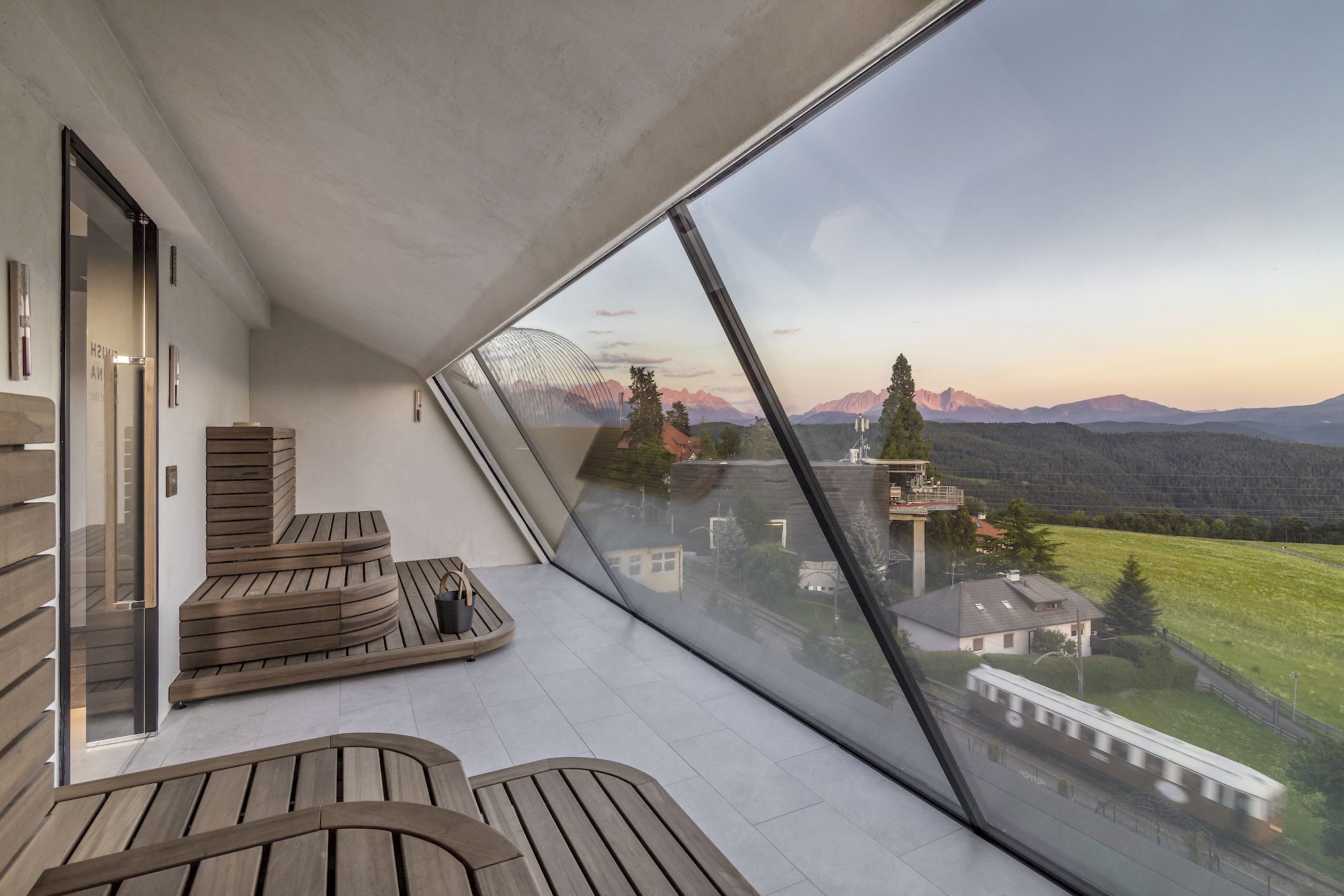 Sauna mit Panoramablick auf Berge und Wälder bei Sonnenuntergang.