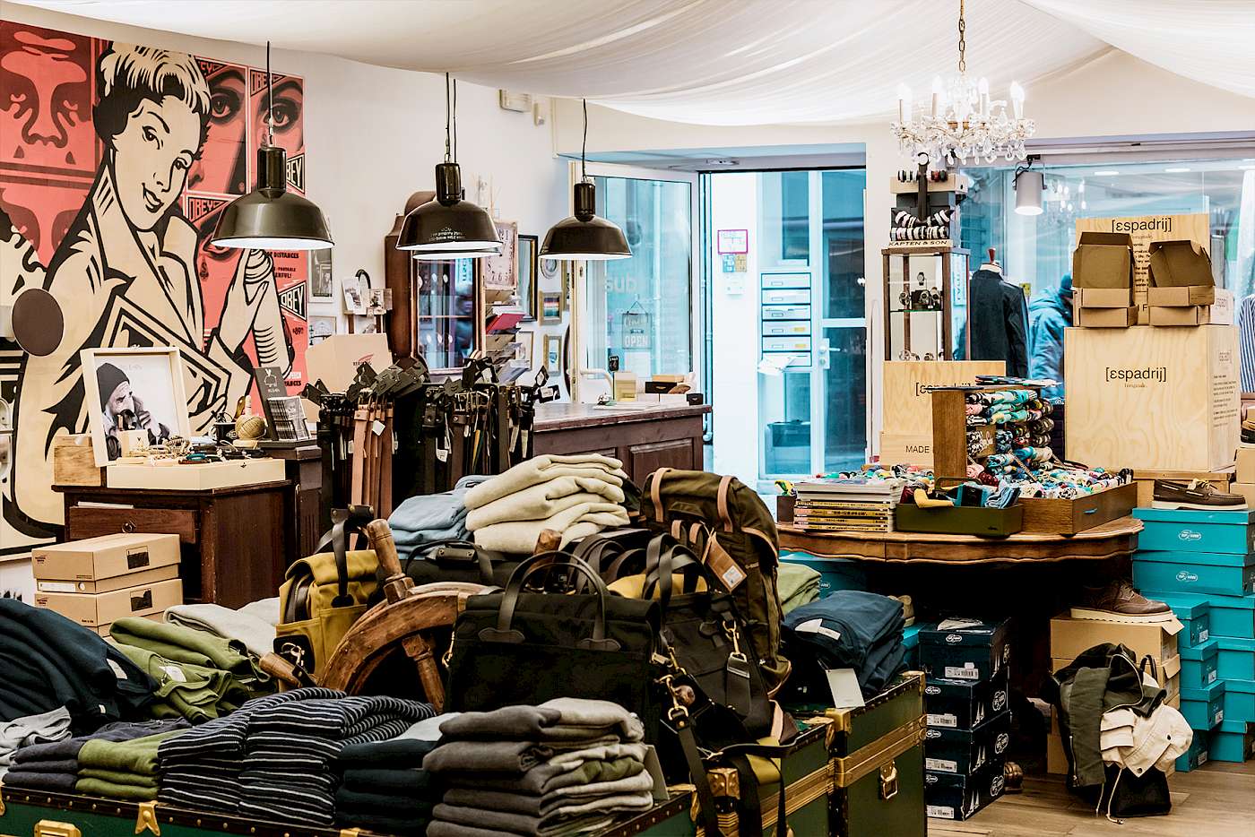 Eleganter Laden mit Kleidung und Accessoires in Regalen, im Hintergrund ein Kunstwerk an der Wand.