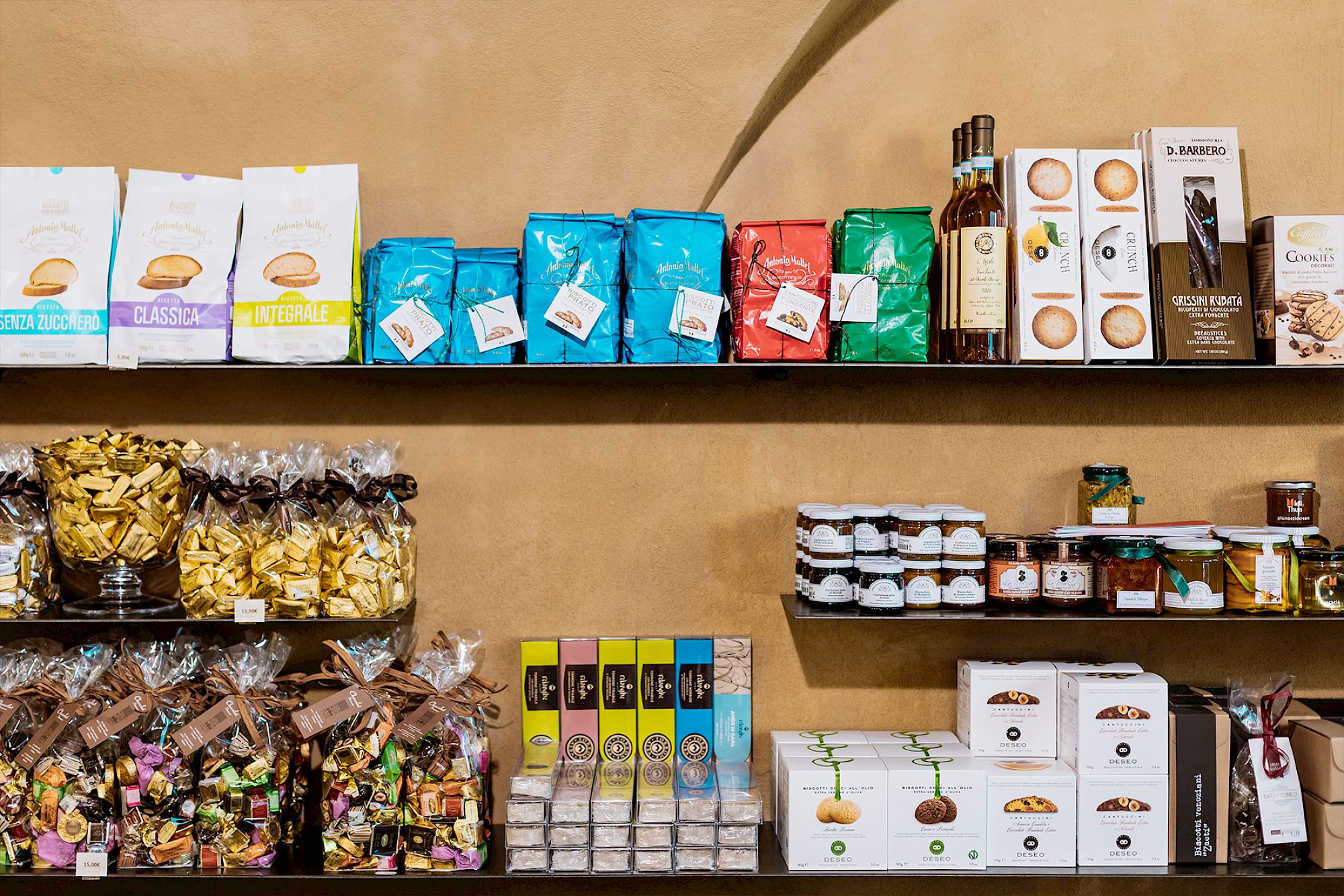 Regale mit verschiedenen Lebensmitteln, darunter Pasta, Marmeladen und andere Feinkostprodukte.