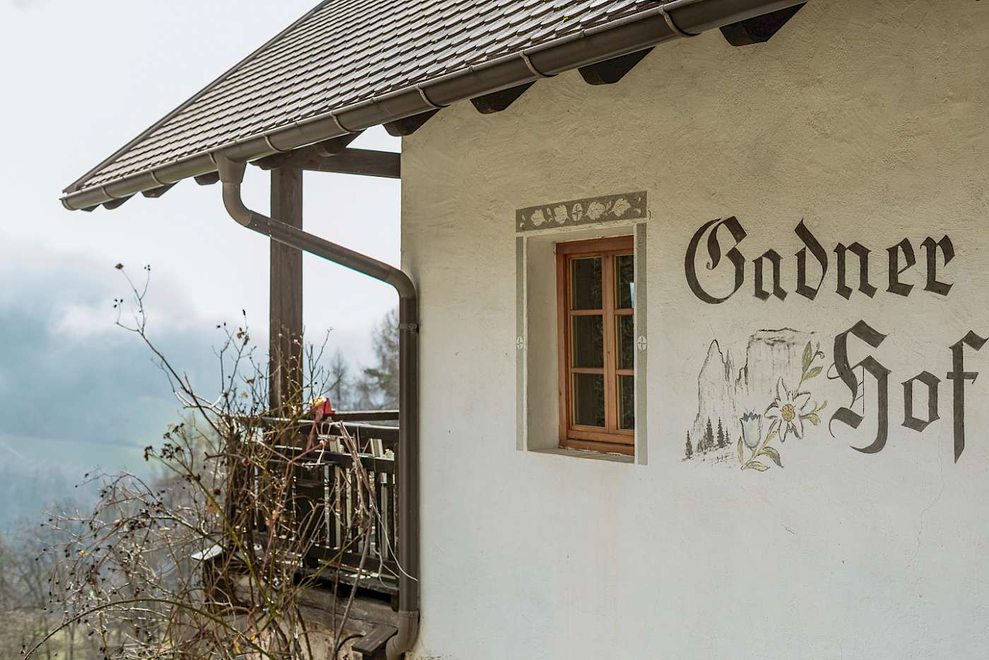 Ein traditionelles Gebäude mit der Aufschrift "Gadner Hof" an der Wand, umgeben von einer malerischen Landschaft.