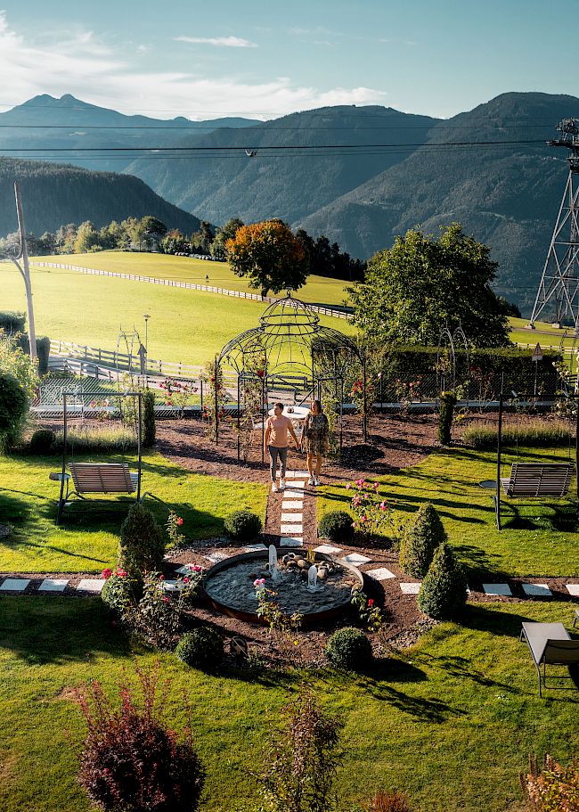 Ein Paar spaziert durch den gepflegten Garten vom Gloriette Guesthouse mit Blick auf eine malerische Berglandschaft.