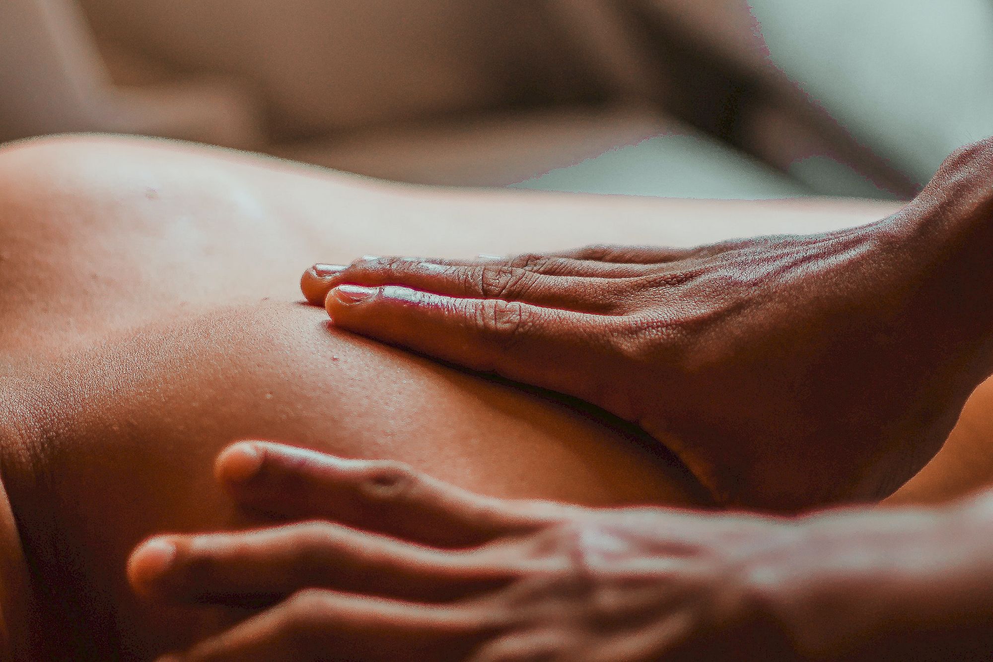Two hands massage a back, relaxed atmosphere in a warmly lit room at Gloriette Guesthouse.