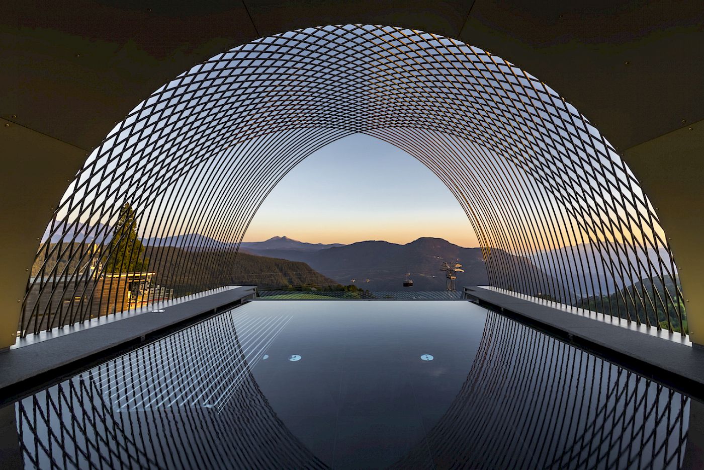 Infinity pool con vista su un paesaggio montuoso al tramonto. Design futuristico.